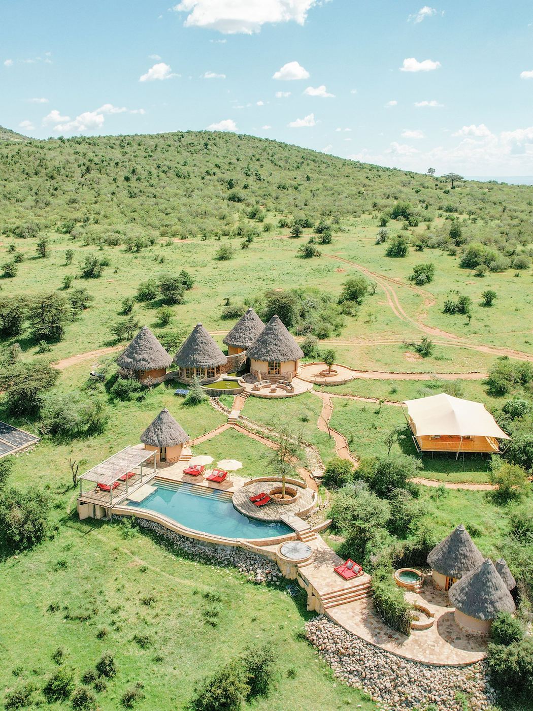 Aerial view of the spa at Mara Bushtops, thatched rondavels around a pool on a green hillside
