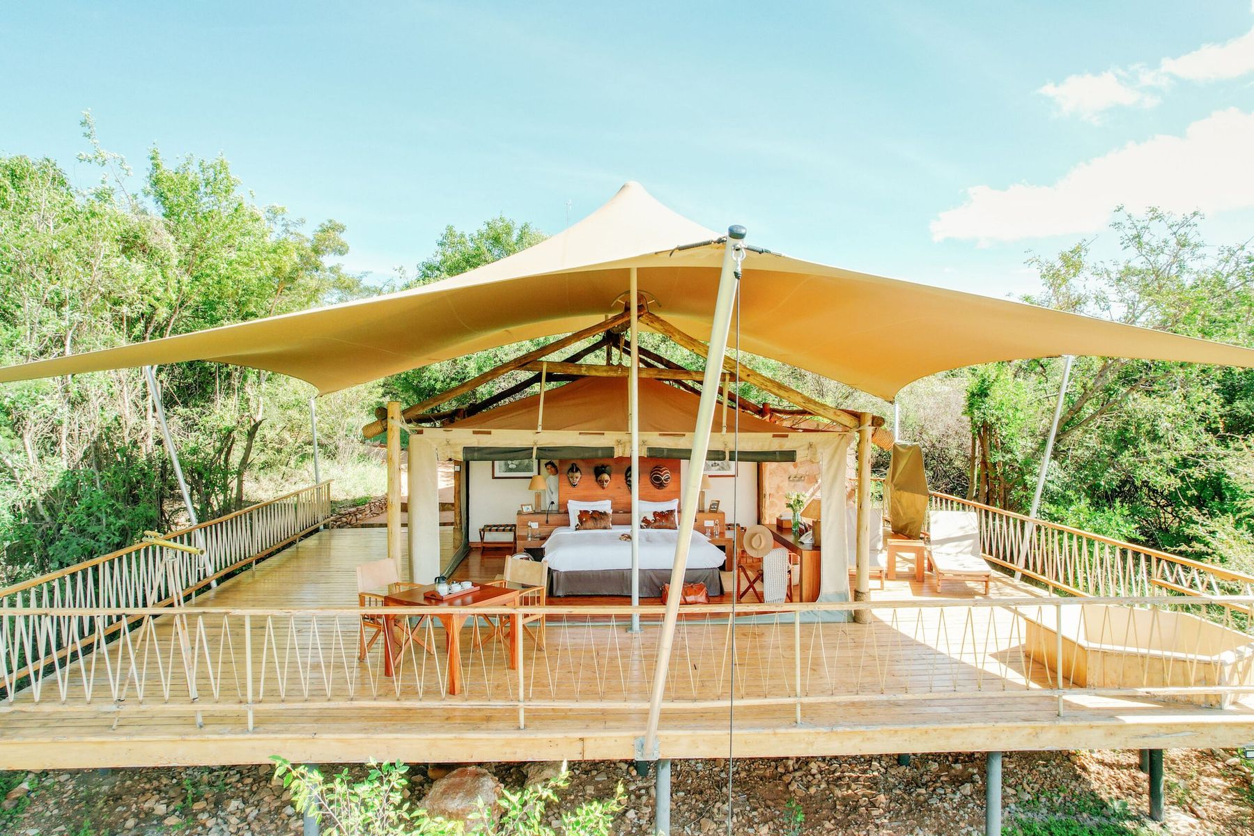 A tented suite at Mara Bushtops under a sweeping canvas roof, raised on a wooden deck among trees