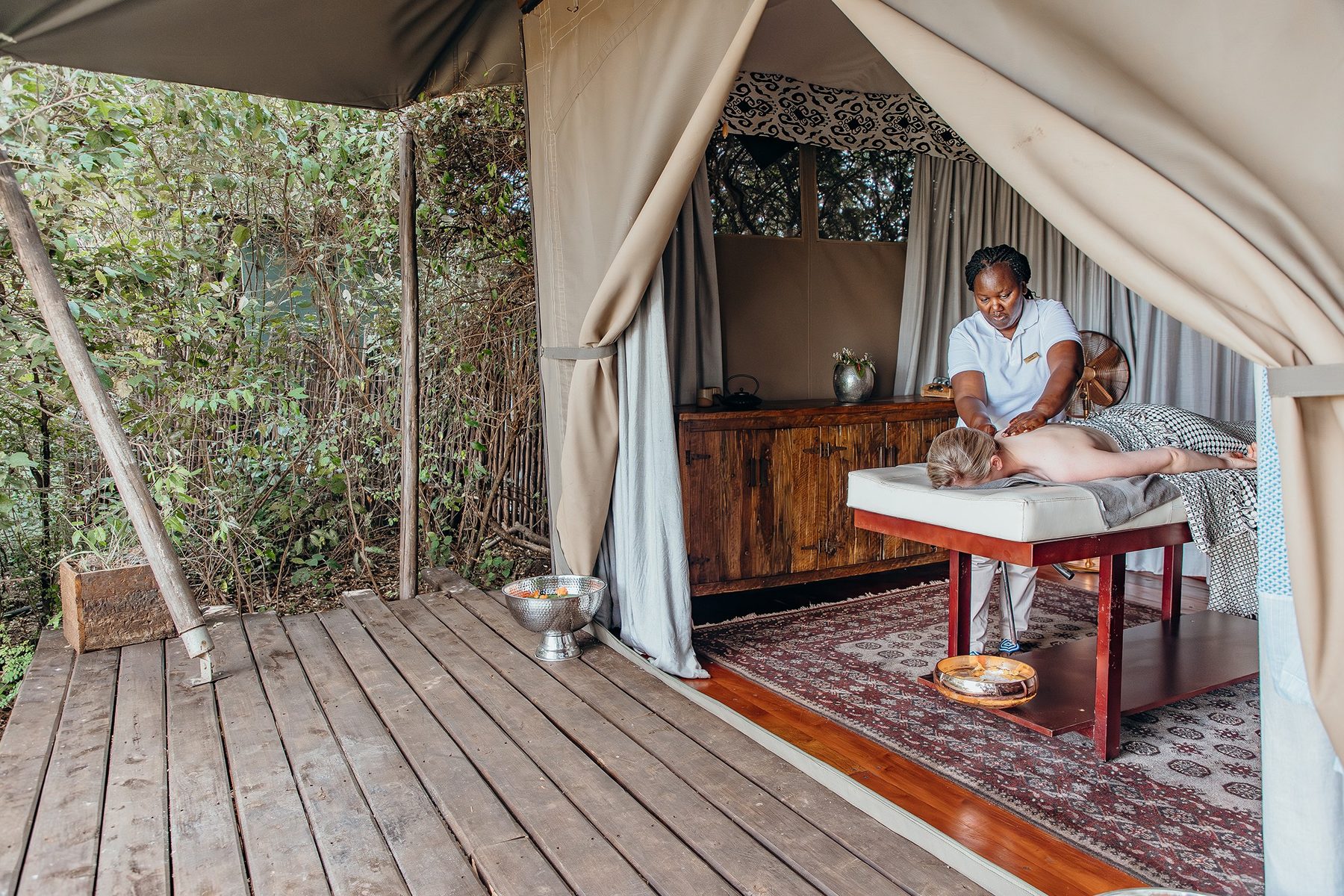 Massage on a wooden deck under canvas at Mara Plains Camp, with the forest just beyond