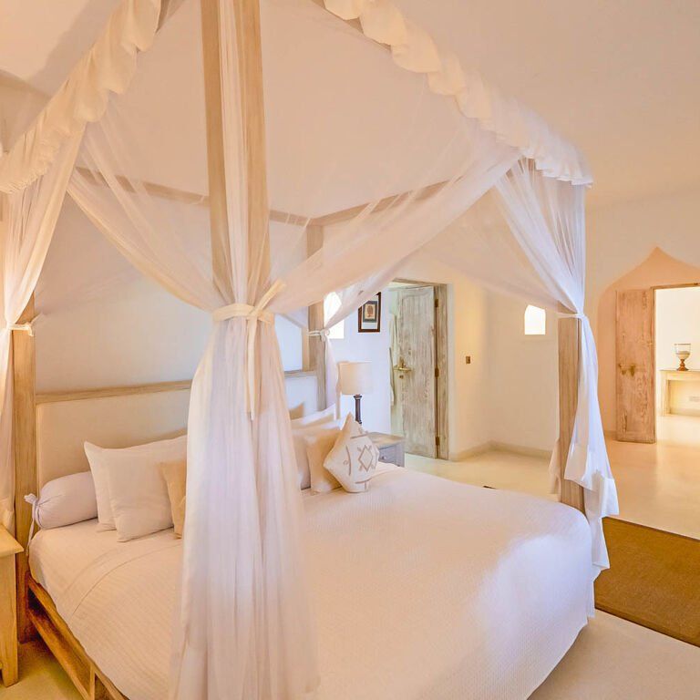 Bedroom at Medina Palms with a white four-poster bed draped in netting