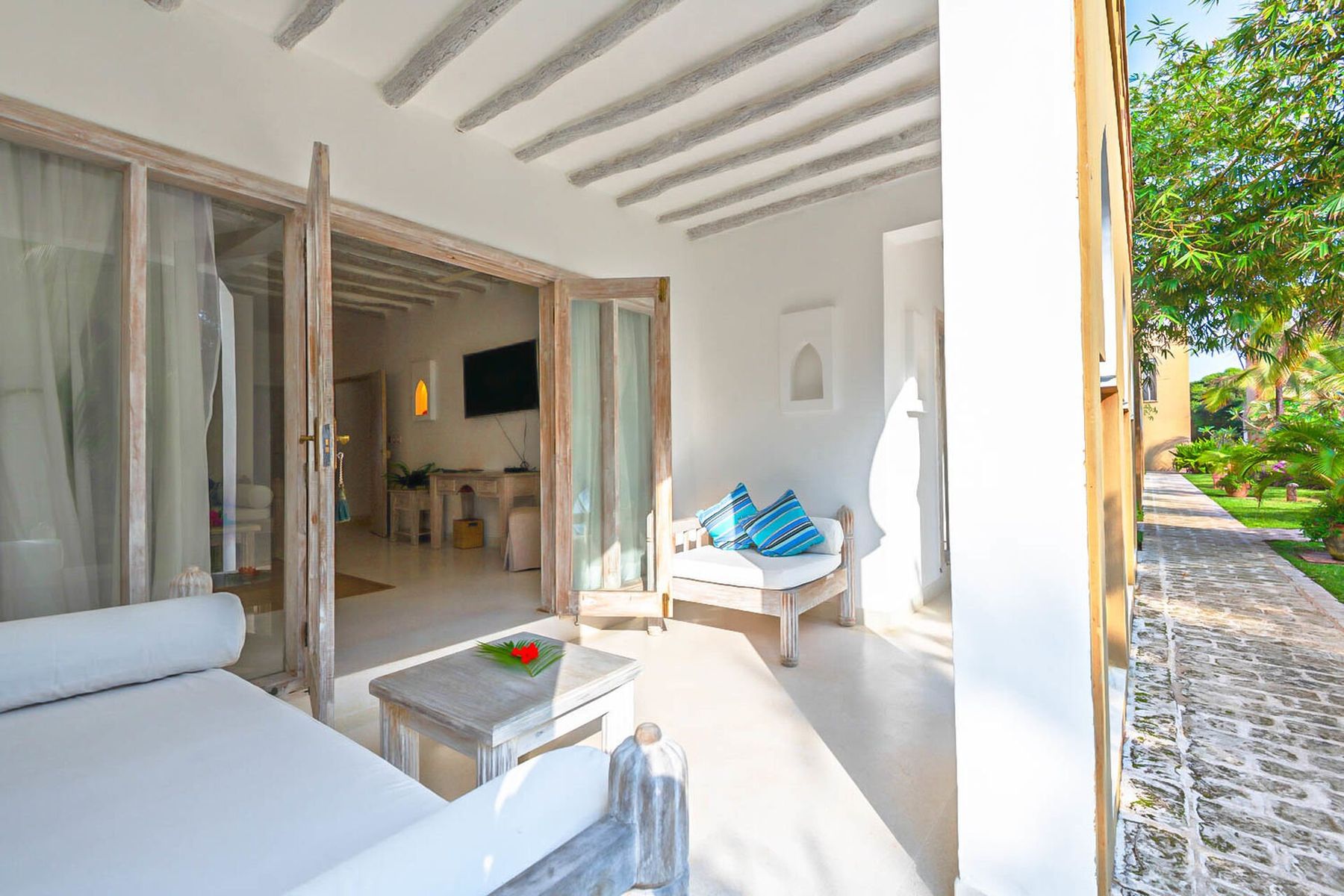 Veranda of a suite at Medina Palms with a cushioned daybed and doors open into a white room