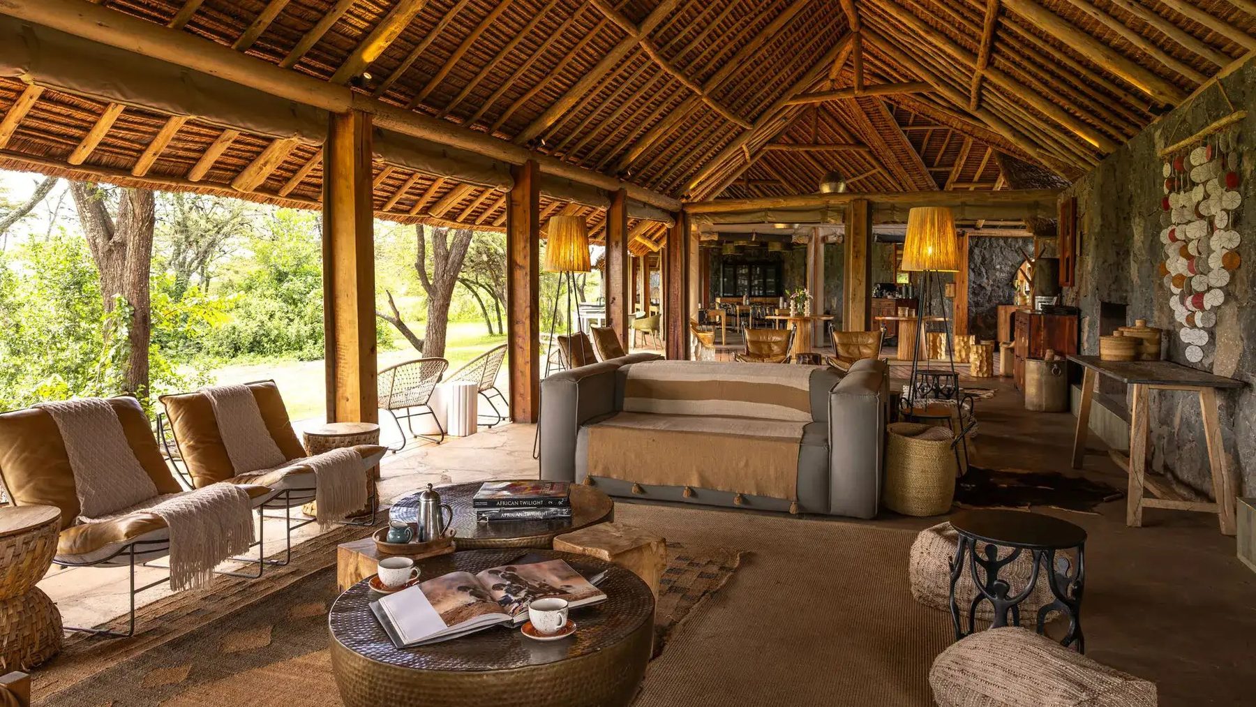 Lounge at Naboisho Camp with leather armchairs, a sofa and a low table beneath a timber and thatch ceiling