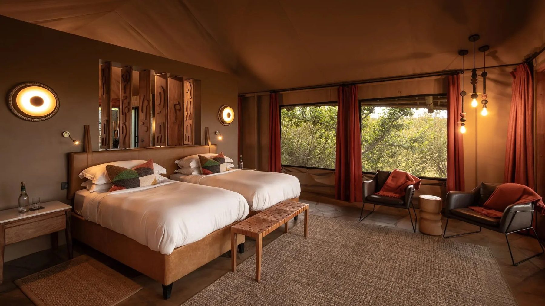 Twin tent at Naboisho Camp with two beds, armchairs and wide windows looking onto green bush