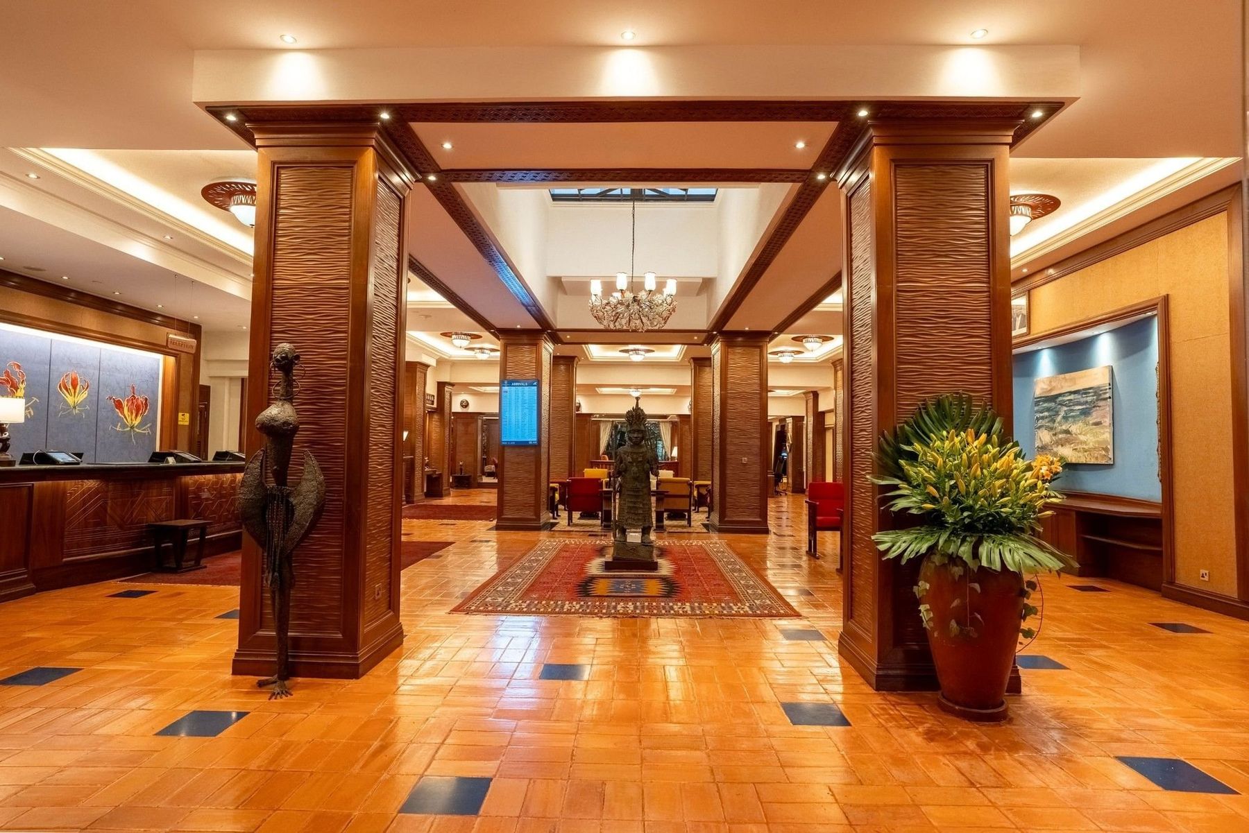 The lobby at Nairobi Serena Hotel, with carved wooden pillars, a sculpture and a patterned rug