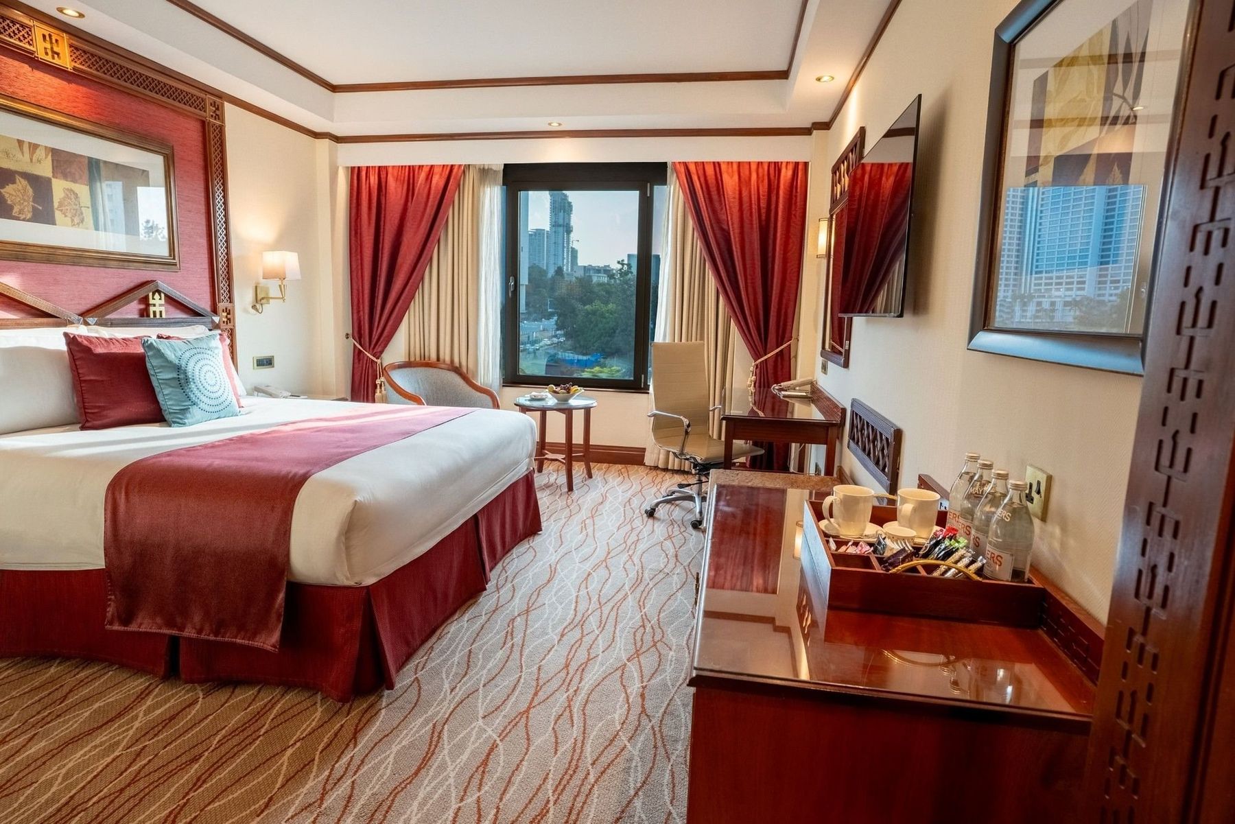 Guest room at Nairobi Serena Hotel with a large bed, red curtains and a window onto the city