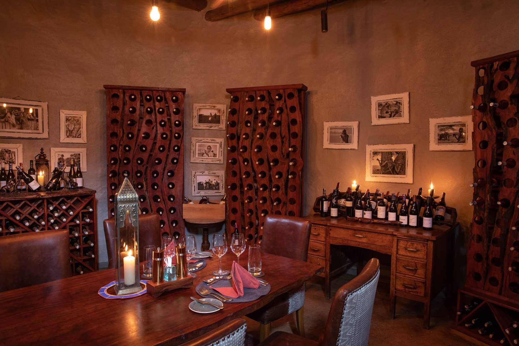 Candlelit table in the wine cellar at ol Donyo Lodge, with racks of bottles and framed pictures