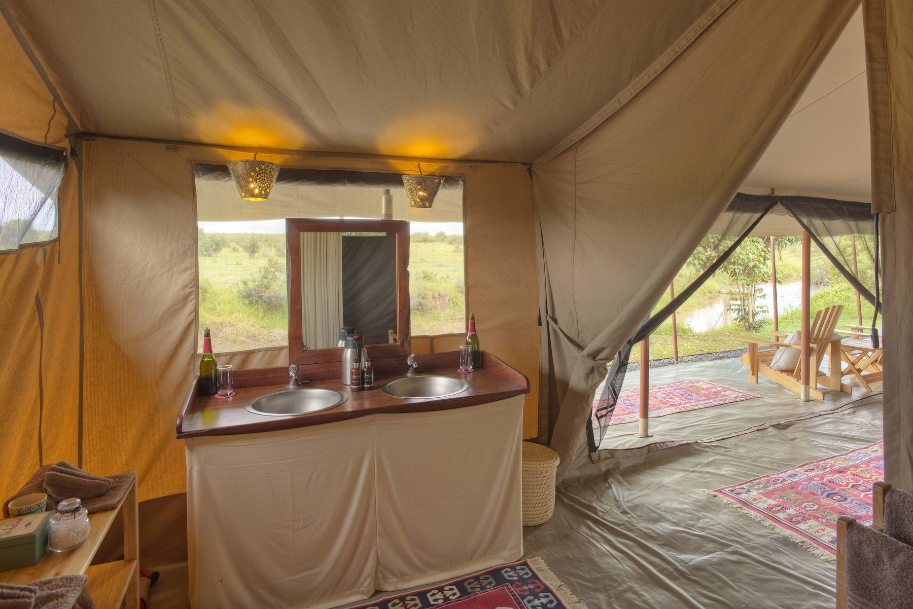 Tented bathroom at Ol Pejeta Bush Camp with twin basins in a wooden vanity beneath a window onto the bush