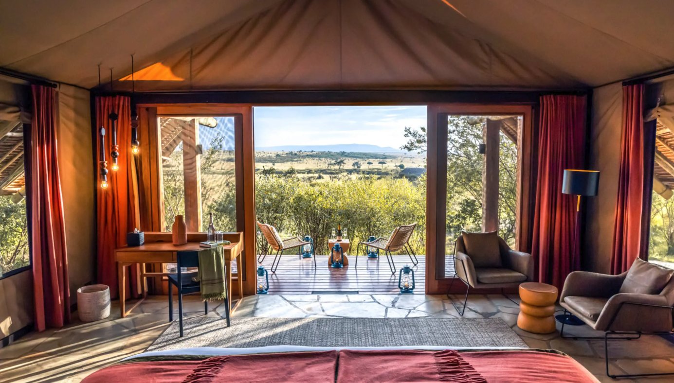 Tent bedroom with open doors onto a deck looking over bush and plains at Naboisho Camp