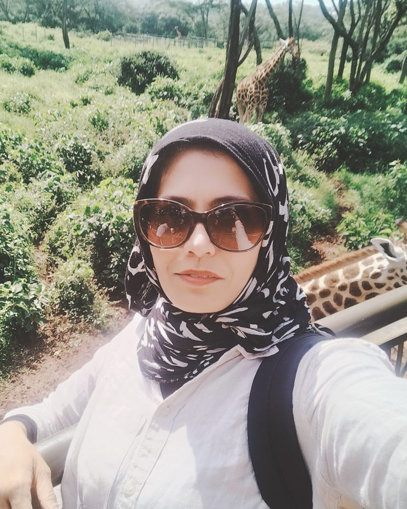 Arefa Jagani, Managing Director, on a viewing platform with giraffes behind her