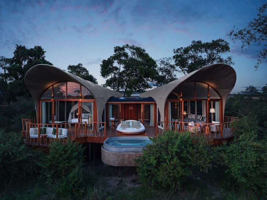 Tented suite with two curved canvas roofs and a plunge pool at dusk at The Ritz-Carlton, Masai Mara Safari Camp