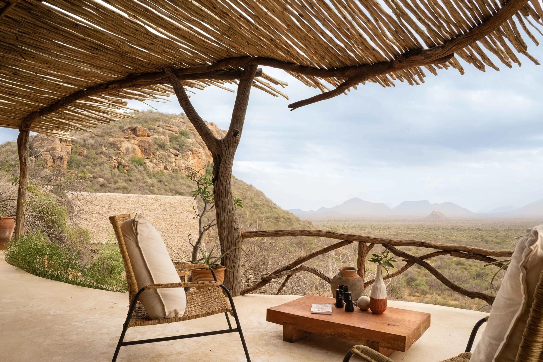 Wicker chair and low wooden table under a thatched shade at Reteti House, overlooking the valley below