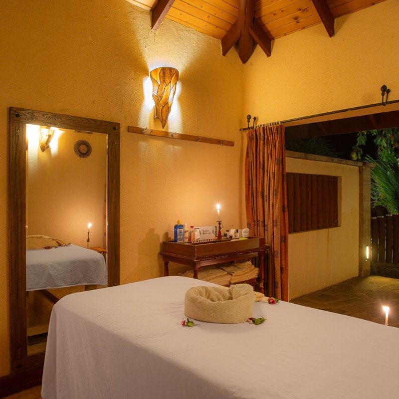Candlelit spa treatment room at Samburu Simba Lodge with a massage bed and warm ochre walls