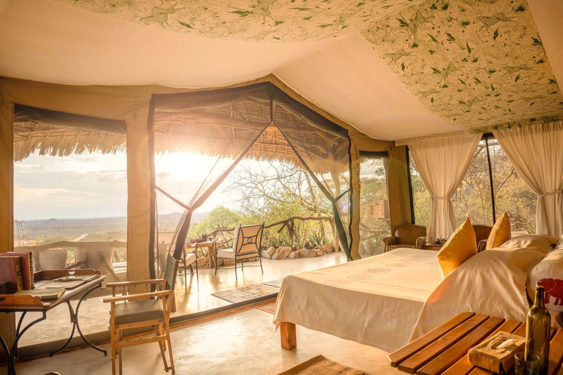 Tent at Sarara Camp with a large bed, mesh walls and a thatched roof, sunlight streaming in from the bush
