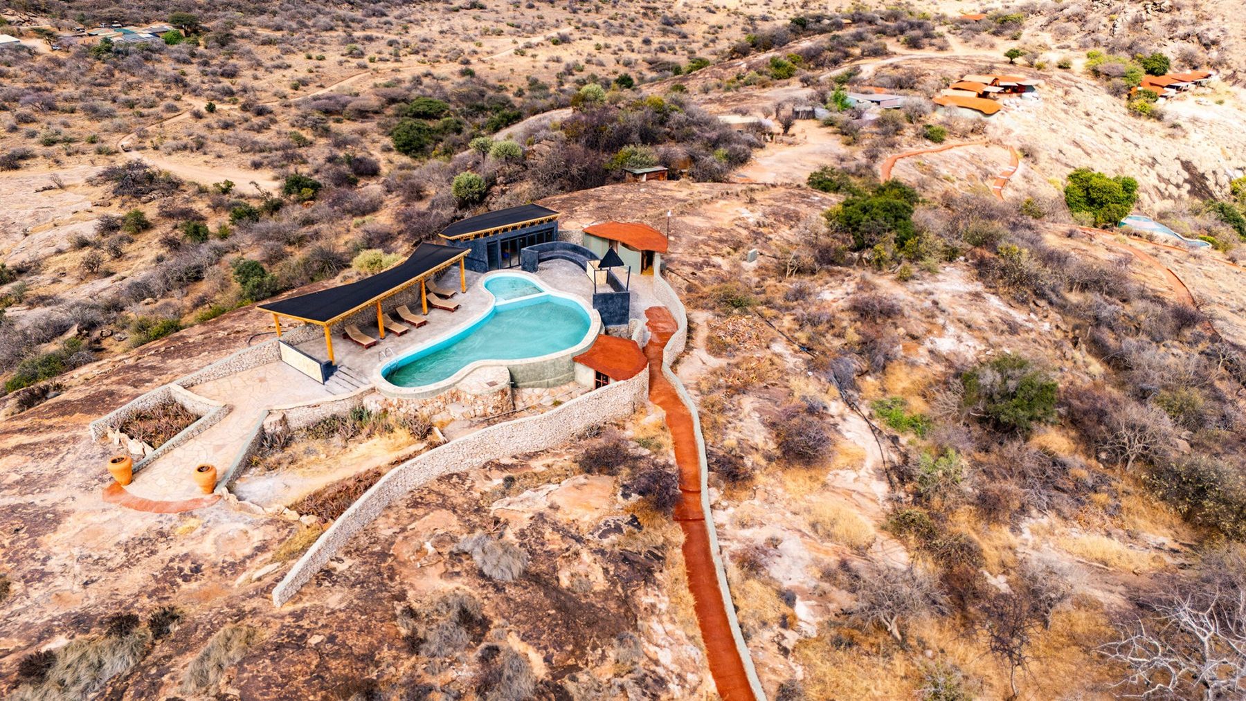Aerial view of the pool and buildings of Saruni Samburu on a rocky hilltop in dry bush
