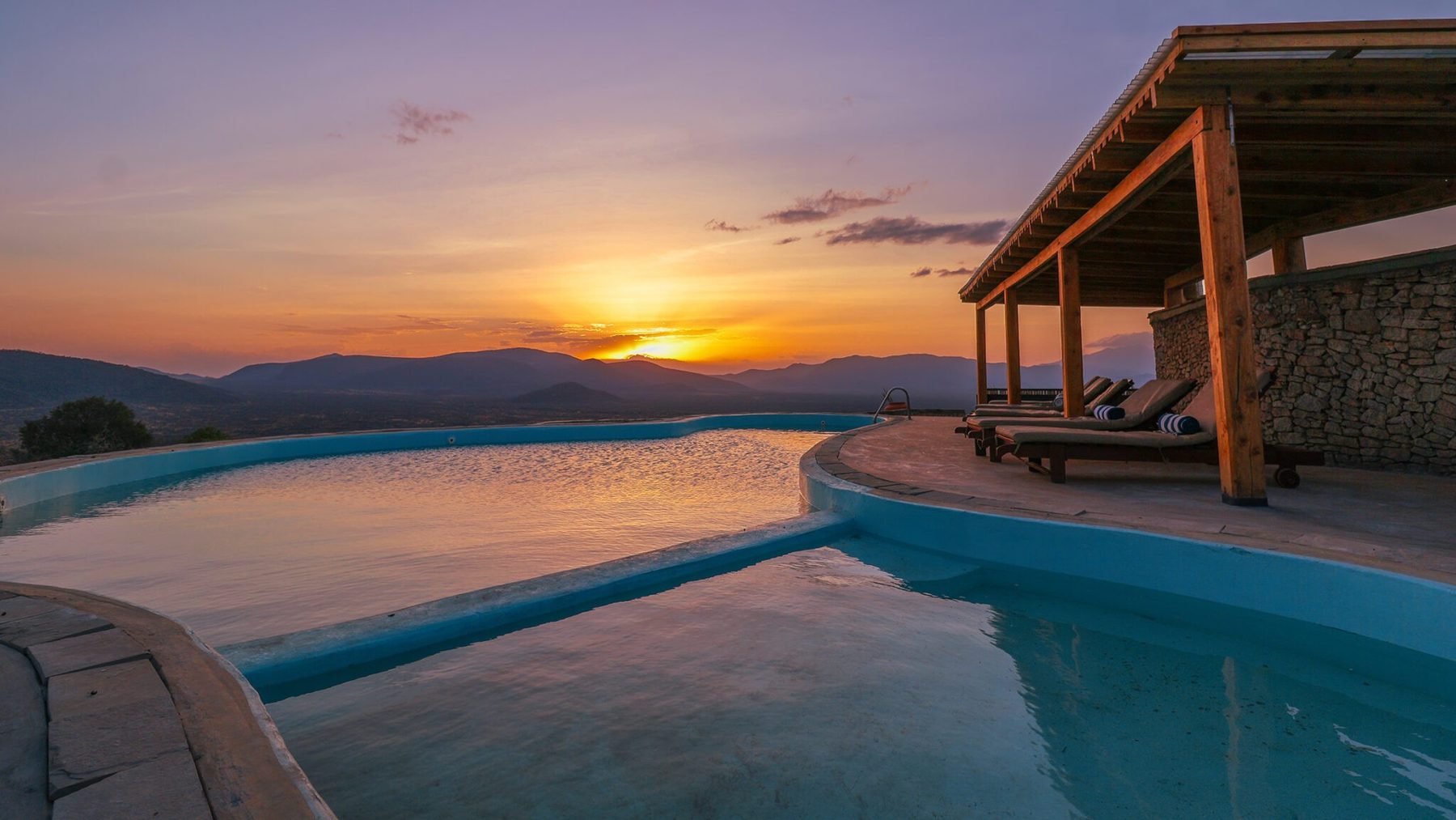 Infinity pool and shaded pavilion at Saruni Samburu as the sun sets over distant hills