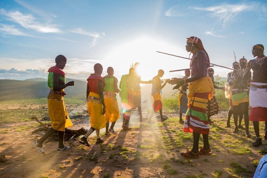 Samburu men and women dancing on open ground in the low sun near Saruni Samburu