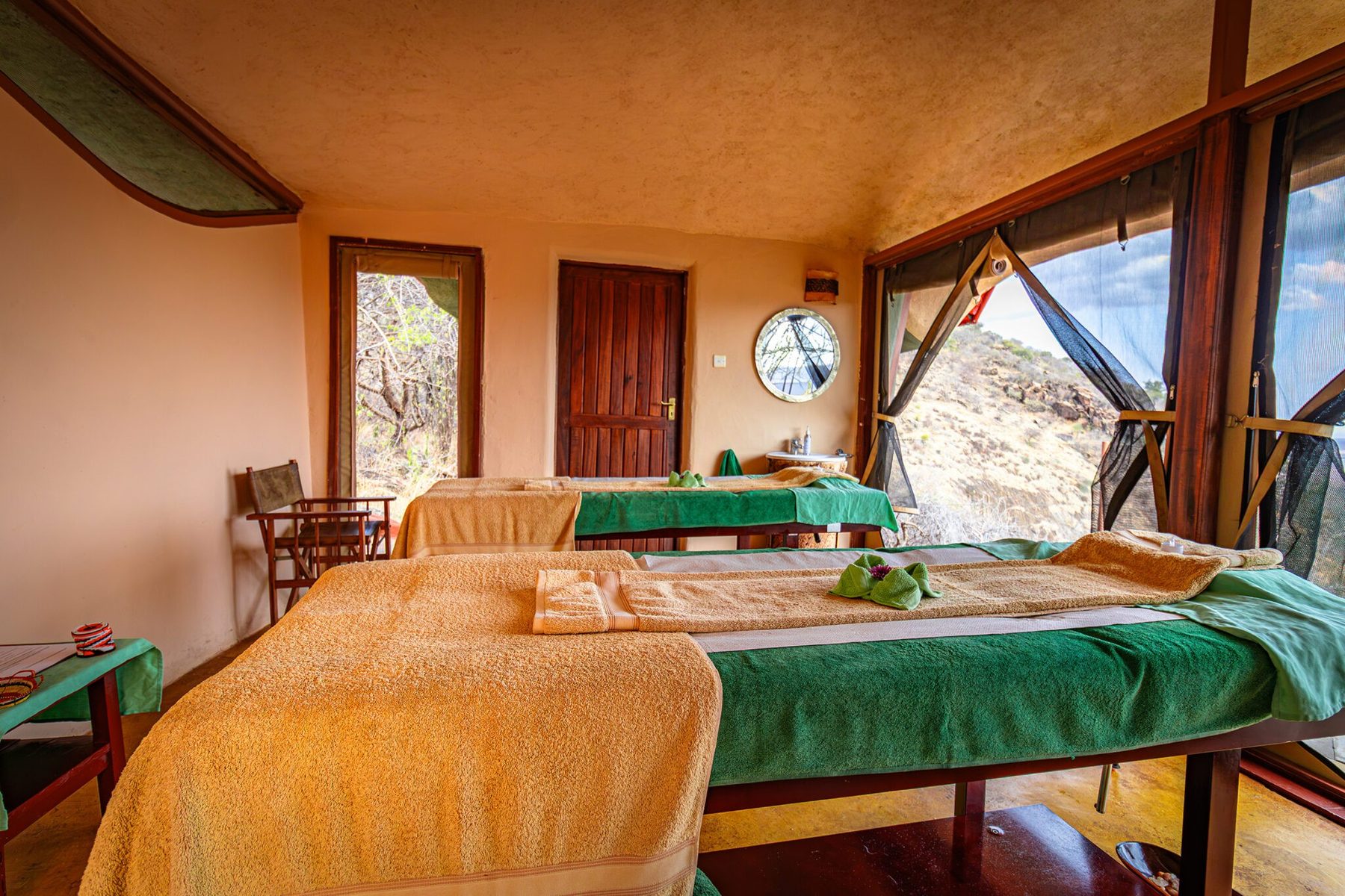 Massage beds laid with towels in the spa at Saruni Samburu, with windows onto the rocks