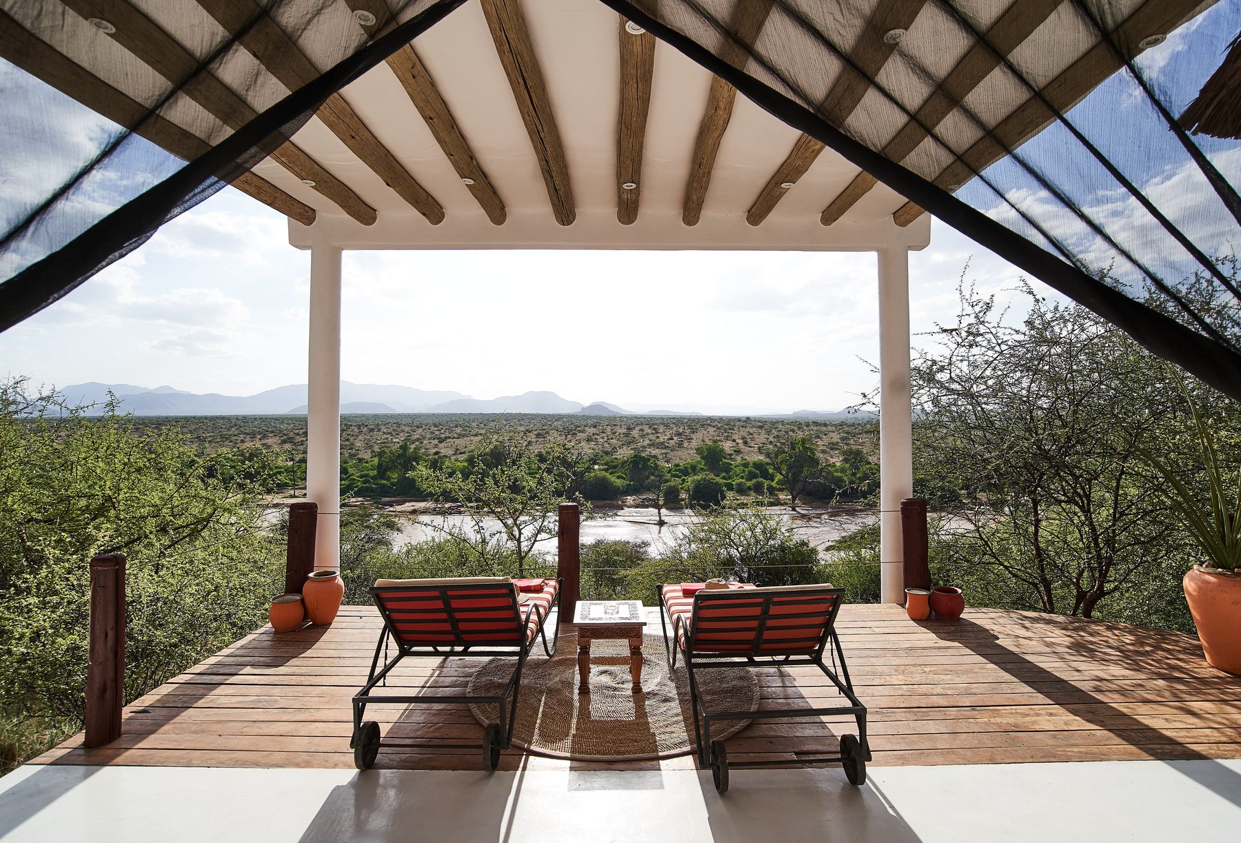Two loungers on a shaded deck at Sasaab looking out over green bush and hills