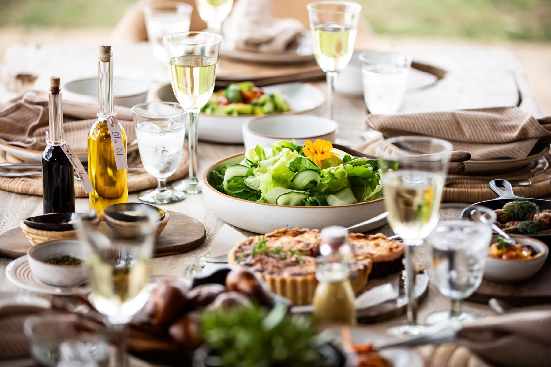 Table laid with salads, a tart, olive oil and glasses of white wine for lunch at Segera Retreat