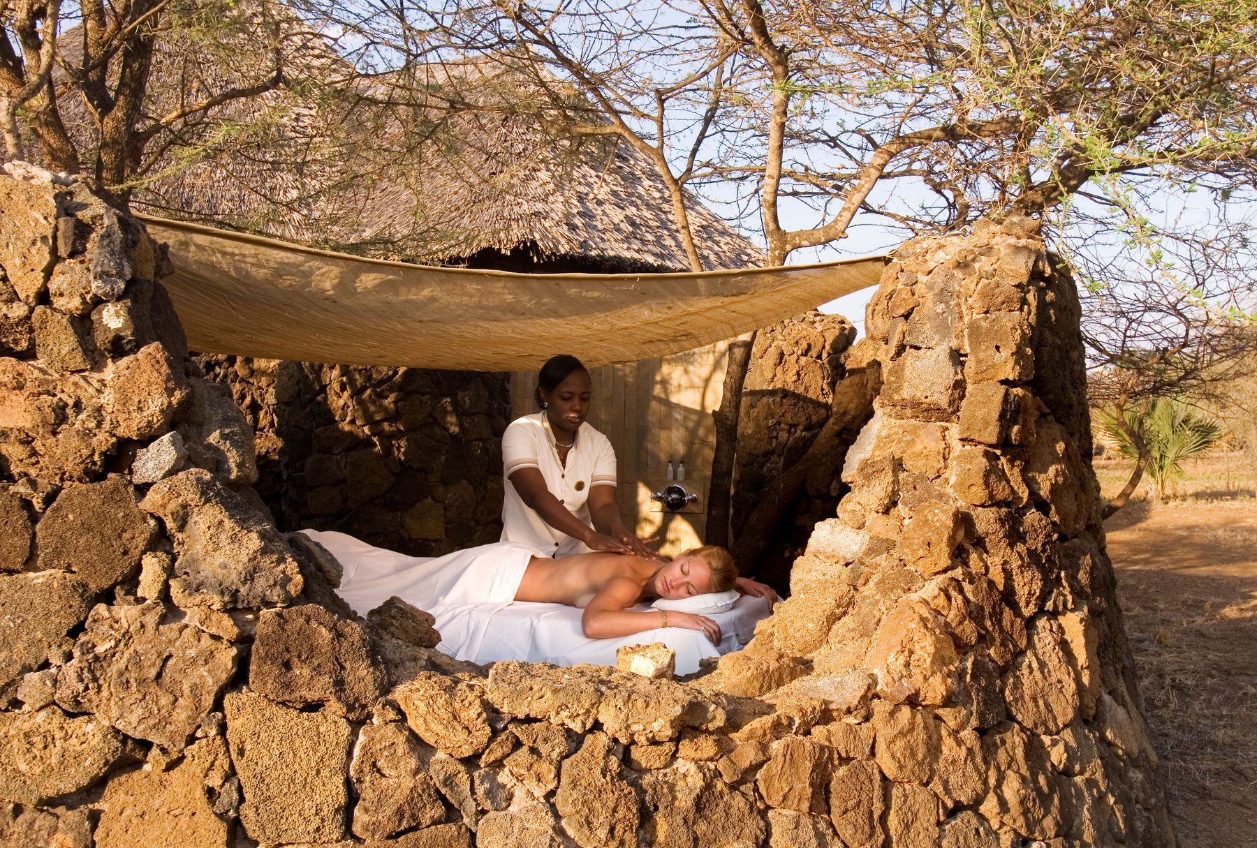 Massage in an open-air spa nook built of stone and thatch at Severin Safari Camp