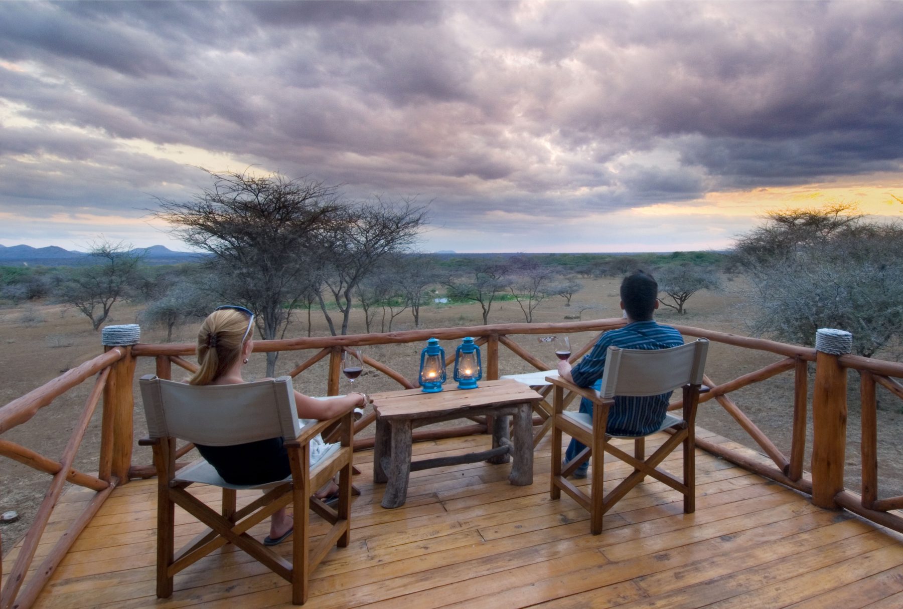 Guests relaxing in canvas chairs on a wooden deck at Severin Safari Camp, looking out over the plains