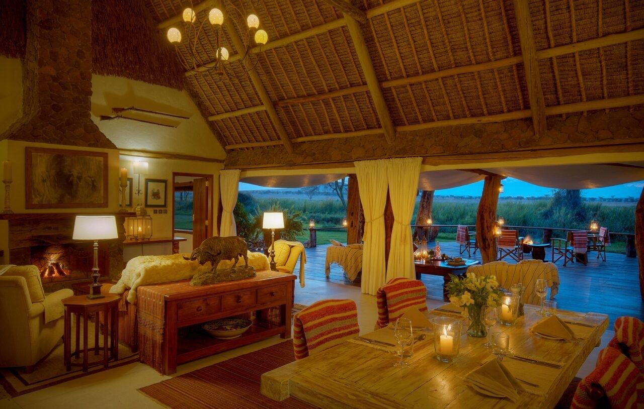 Lounge and dining area under a thatched roof at Sirikoi, with sofas, a laid table and views to the waterhole