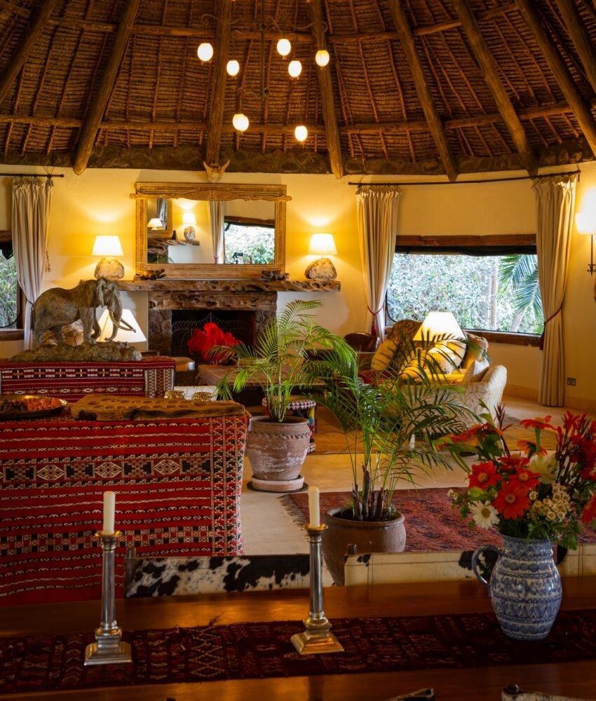 Thatched sitting room at Sirikoi with patterned sofas, flowers, candles and a lit fireplace