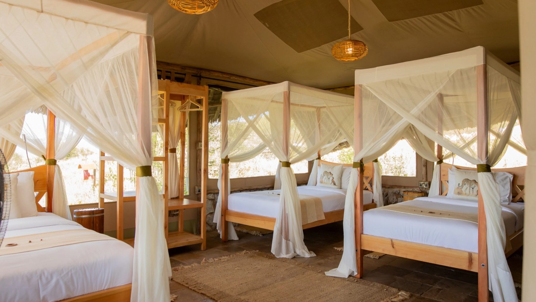 Tent at Soroi Cheetah Tented Camp with three netted four-poster beds under a canvas roof