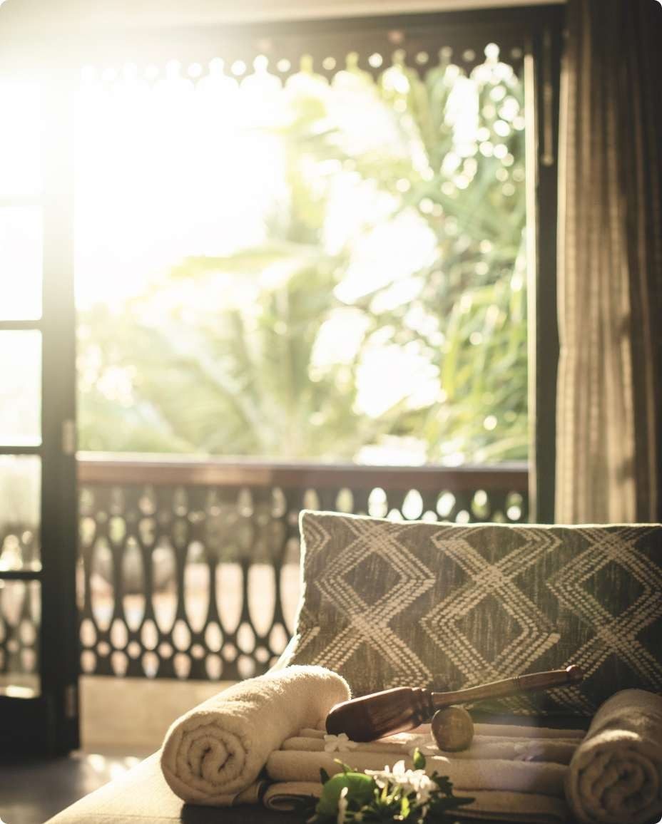Cushioned seat on a balcony with a carved balustrade at Swahili Beach Resort, looking into palm trees