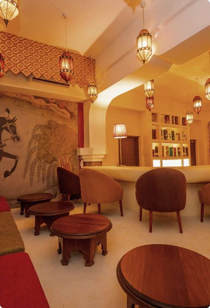 Warmly lit lounge bar at Swahili Beach Resort with wooden chairs, lanterns and carved arches