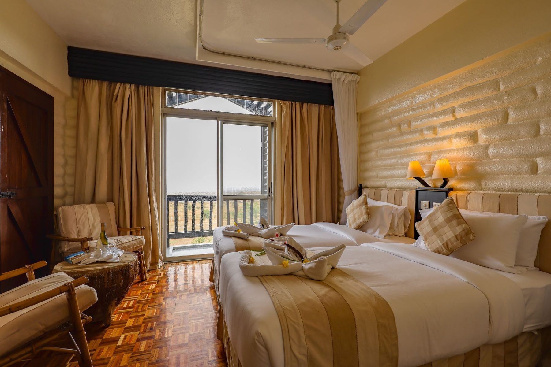 Bedroom at Taita Hills Safari Resort & Spa with a double bed, armchair, wood floors and a balcony door