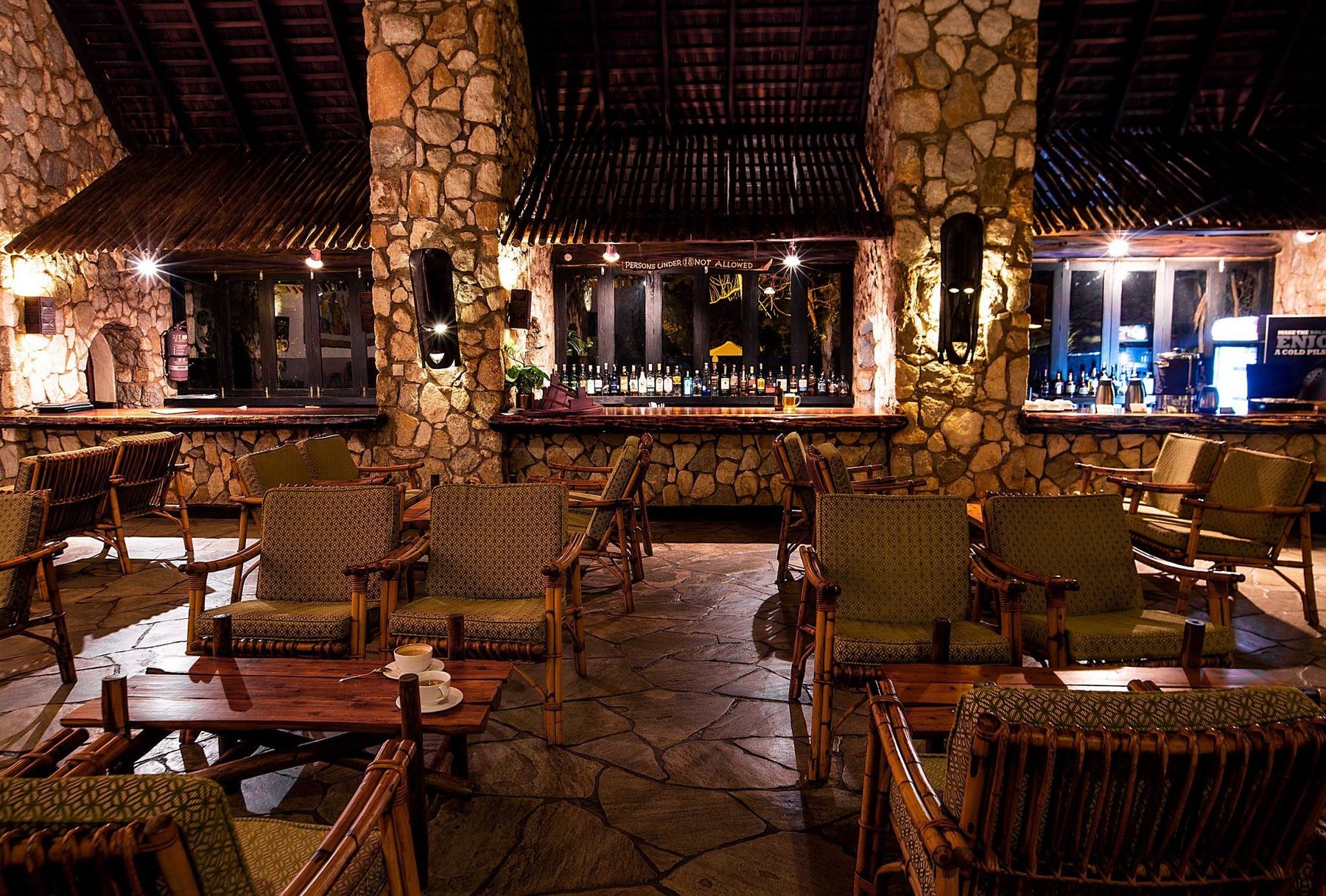 Lounge at Taita Hills Safari Resort & Spa with armchairs and low tables under a thatched roof and stone pillars