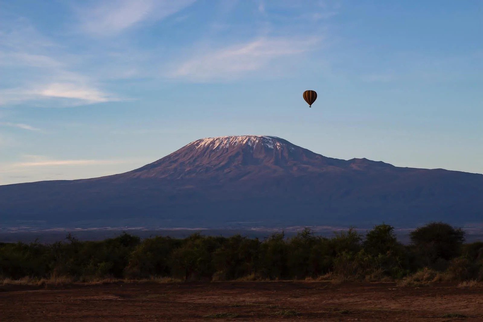 Hot-air balloon drifting beside snow-capped Kilimanjaro above the plains near Tawi Lodge