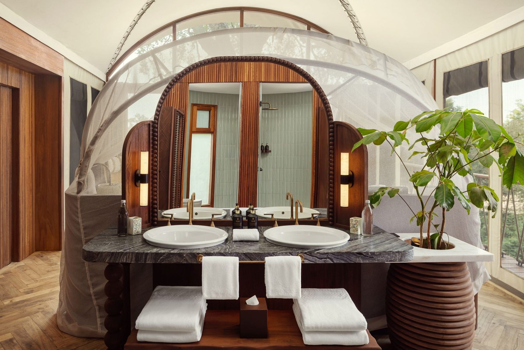 Suite bathroom at The Ritz-Carlton, Masai Mara Safari Camp with twin basins, folded towels and an arched timber surround