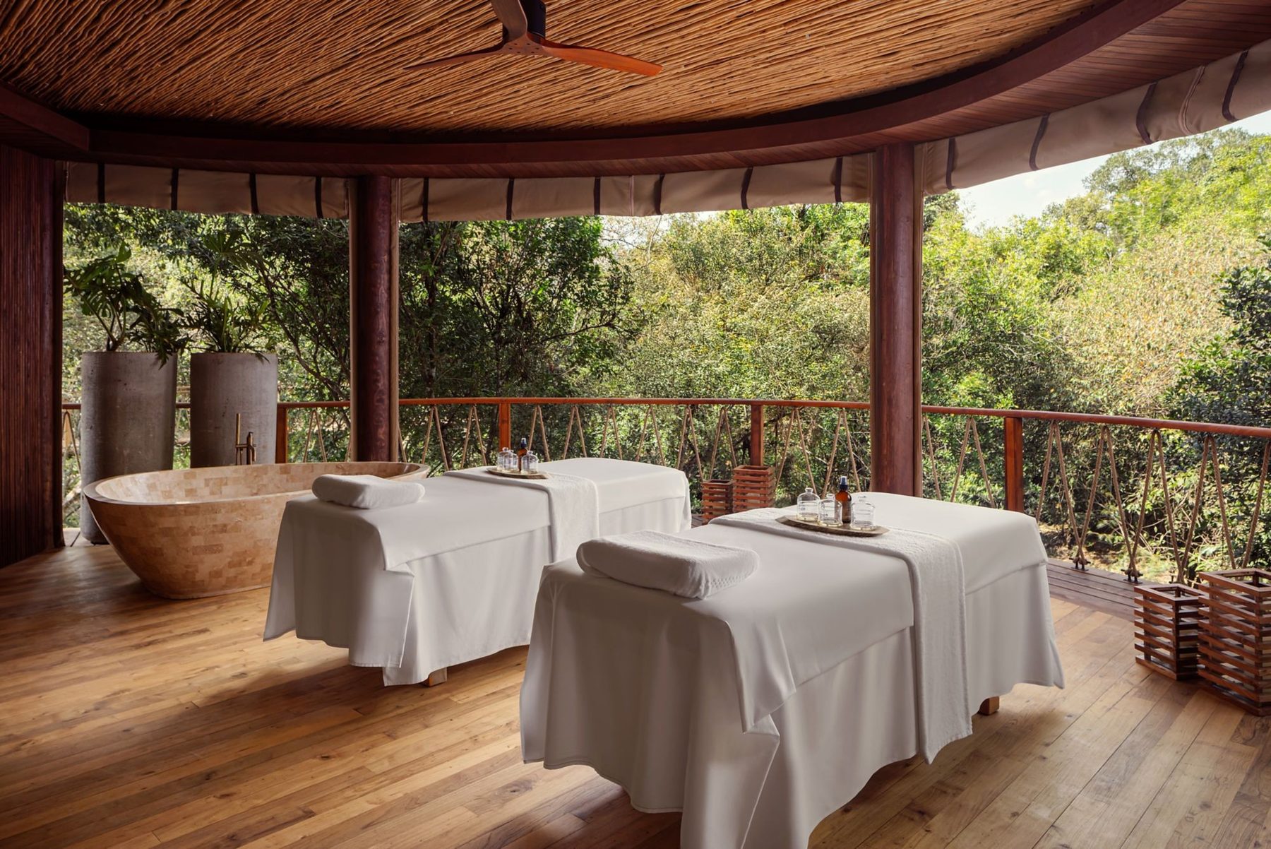 Spa treatment room with two massage beds, open to the trees, at The Ritz-Carlton, Masai Mara Safari Camp